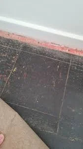 Confirmed dark asbestos-containing floor tiles beneath later floor finish