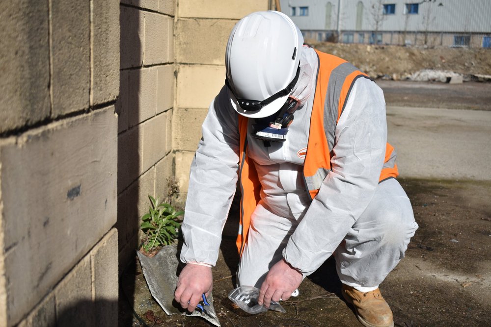 ASM asbestos surveyor inspecting and sampling a suspected asbestos-containing material
