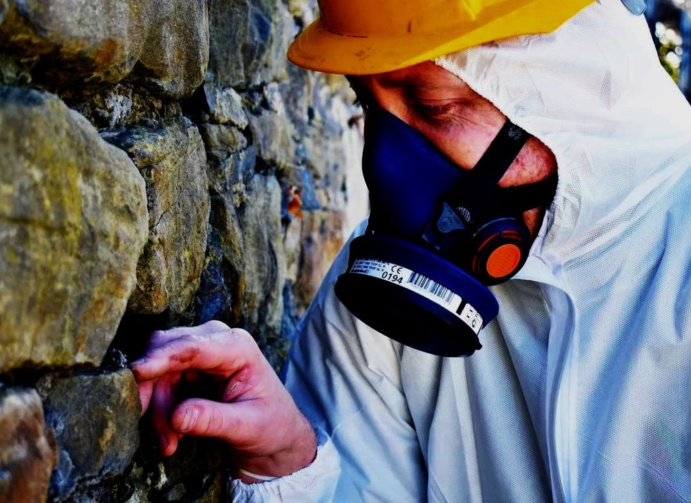 ASM surveyor inspecting a building material while wearing suitable protective equipment
