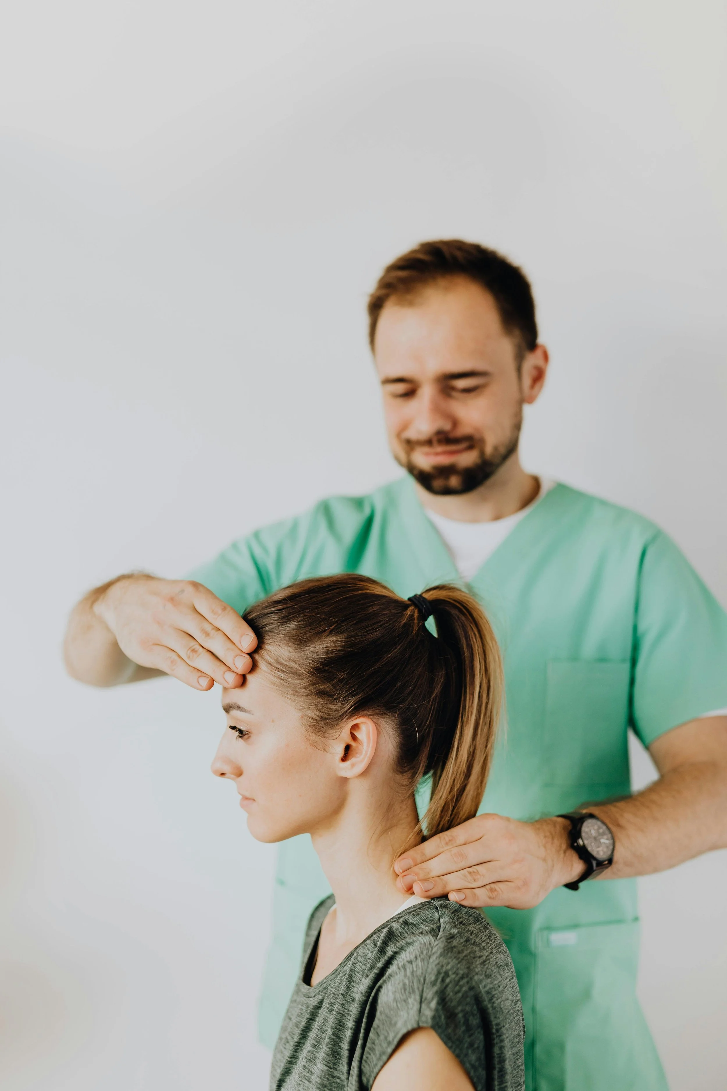 Healthcare professional performing a neck examination on a woman in a clinical setting.
