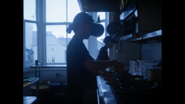 Silhouette of a woman cooking in a kitchen with large windows in the background for a Thai Restaurant in Brighton.