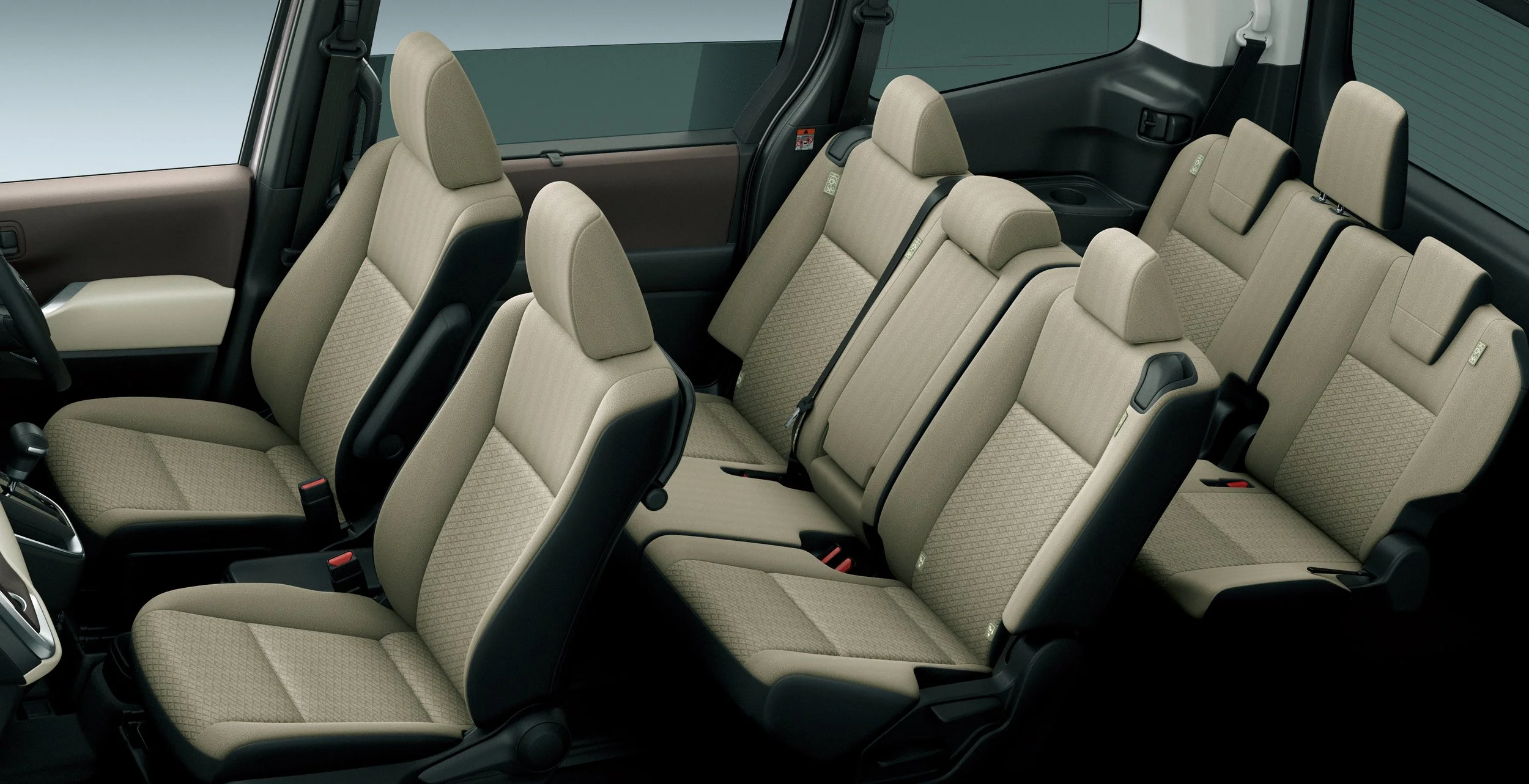 Interior of a car showing multiple beige fabric seats, black seat belts, and a two-tone door panel.