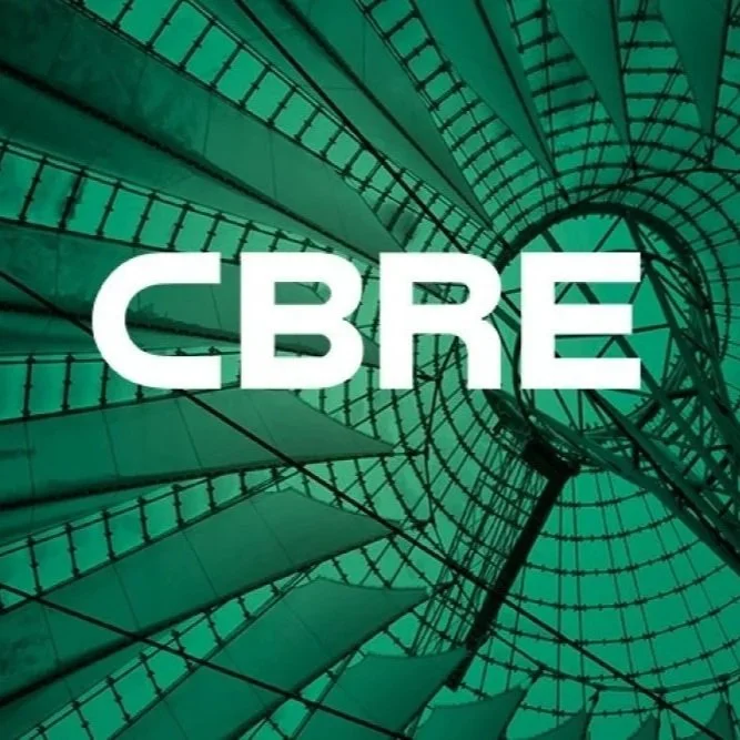 View of a spiral staircase looking up from the bottom with greenish tone, overlaid with the text 'CBRE' in white bold letters.