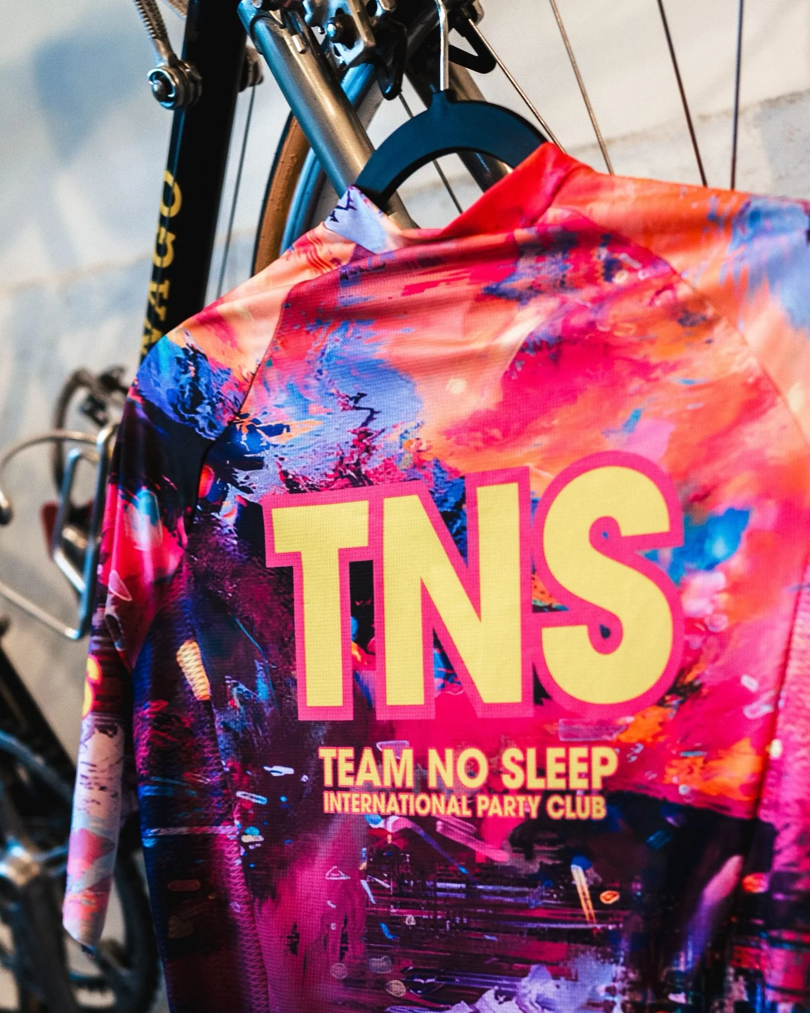 Fiets met een kleurrijke shirt met de tekst 'TNS, Team No Sleep, International Party Club' erop.