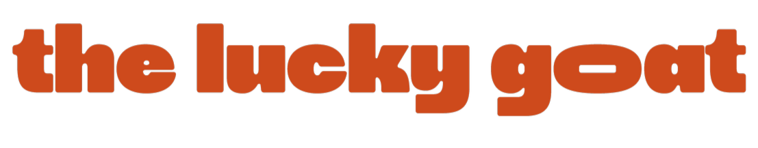 The words "the lucky goat" in bold, lowercase, orange letters on a black background.