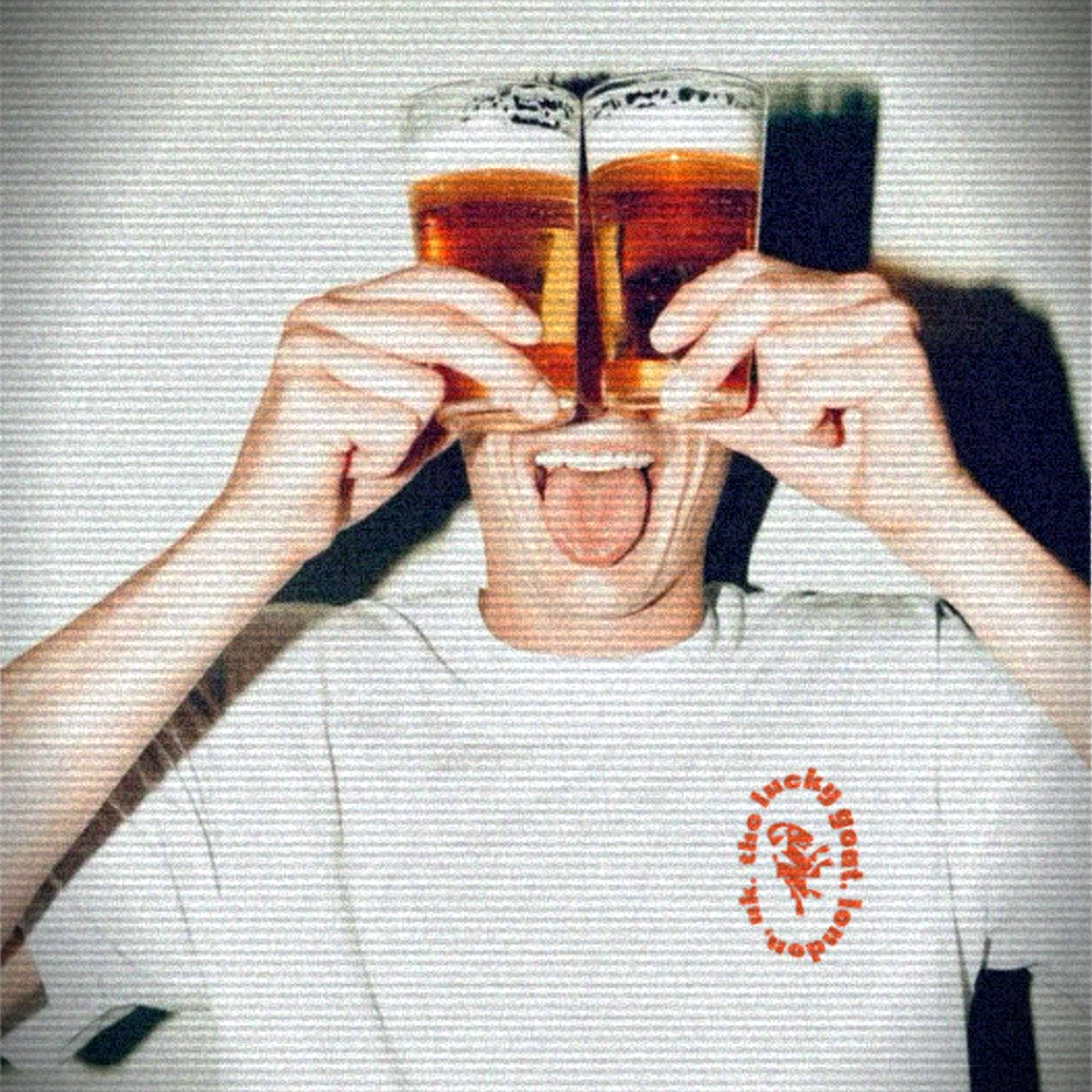 A member of The Lucky Goat's team holding up two glasses of ice cold tank fresh lager up to their eyes, sticking out their tongue, wearing a white T-shirt with The Lucky Goat logo on it.