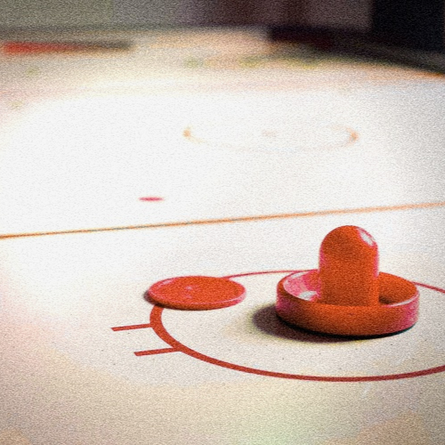 Close-up of a red Air Hockey pusher and puck on one of The Lucky Goat's Air Hockey tables - bookable online.
