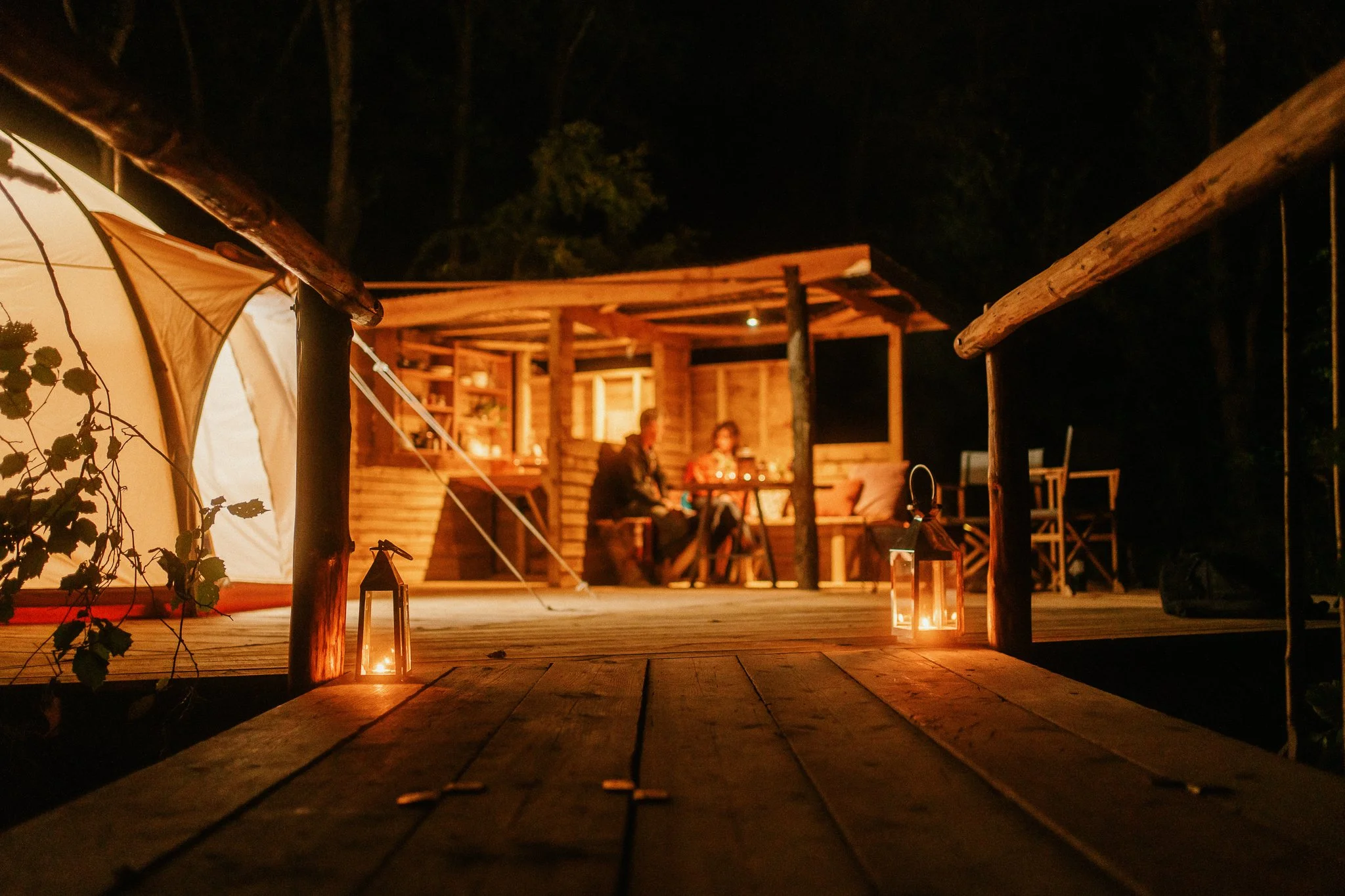 View across the footbridge of the creekside all lit up at night with a couple in the background 