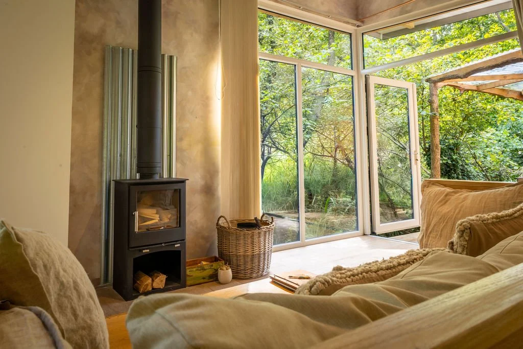 Cosy interior with natural colours and textures, huge windows and wood burner