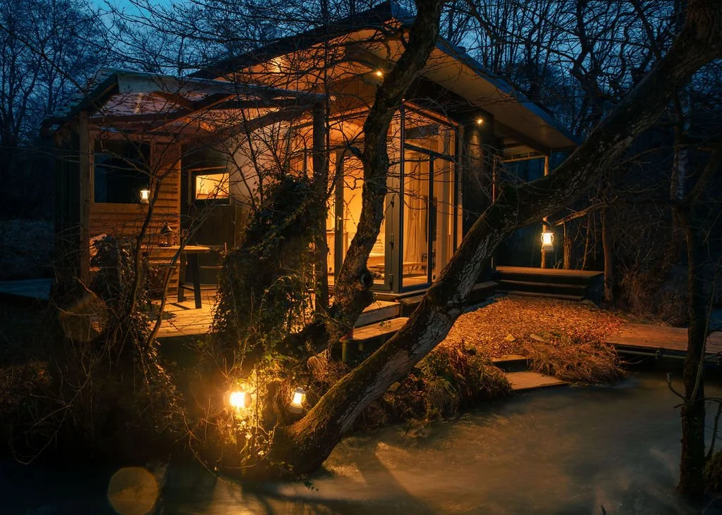Cosy Beck cabin at night with stream flowing by