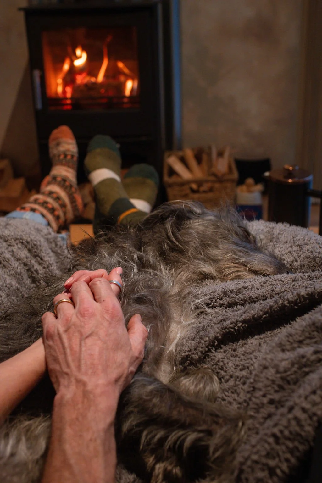a couple cuddled up in front of the fire with a dog in Beck off-grid cabin 