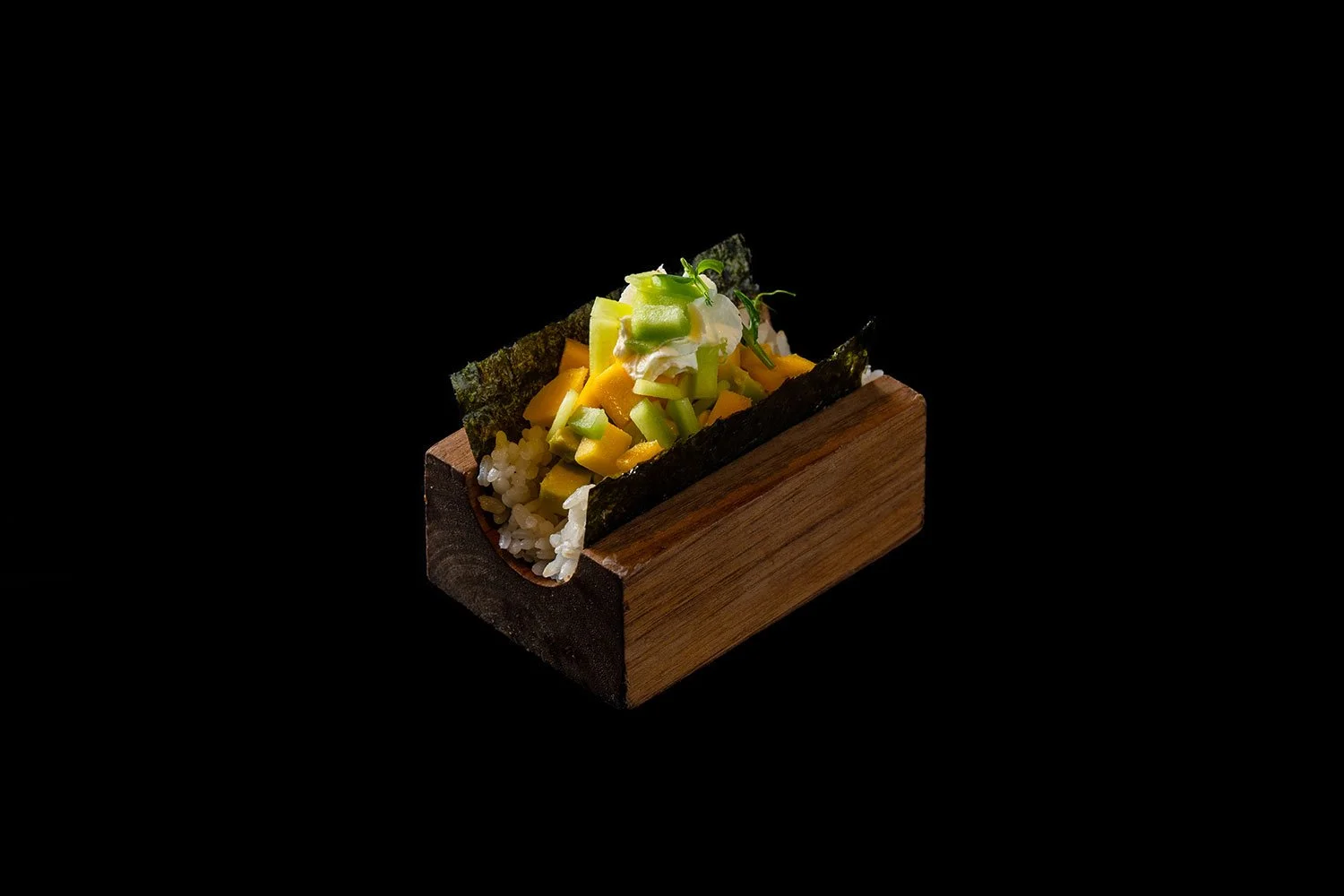 Sushi in einem hölzernen Sushi-Box mit Nori, Reis, Mango, Avocado, und Frühlingszwiebeln auf schwarzem Hintergrund
