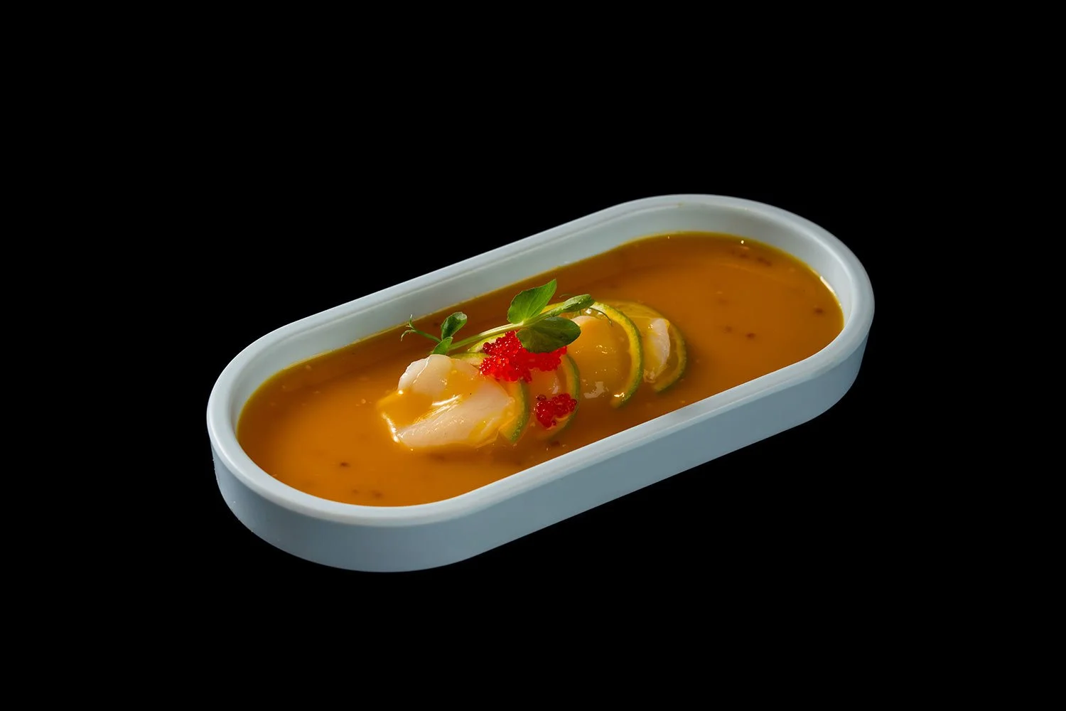 Gekochte Garnelen mit Zitrusfrüchten und Kräutern in einer weißen Schale auf schwarzem Hintergrund.