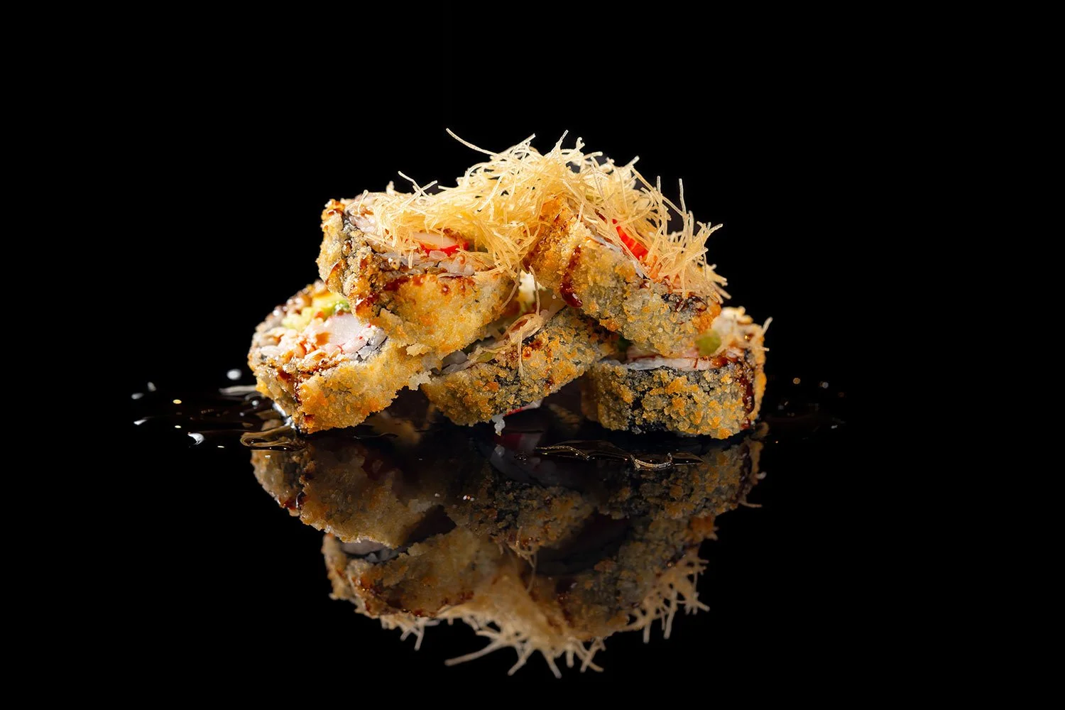 Frittierte Sushi-Rollen mit Toppings auf schwarzem Hintergrund, mit Spiegelung
