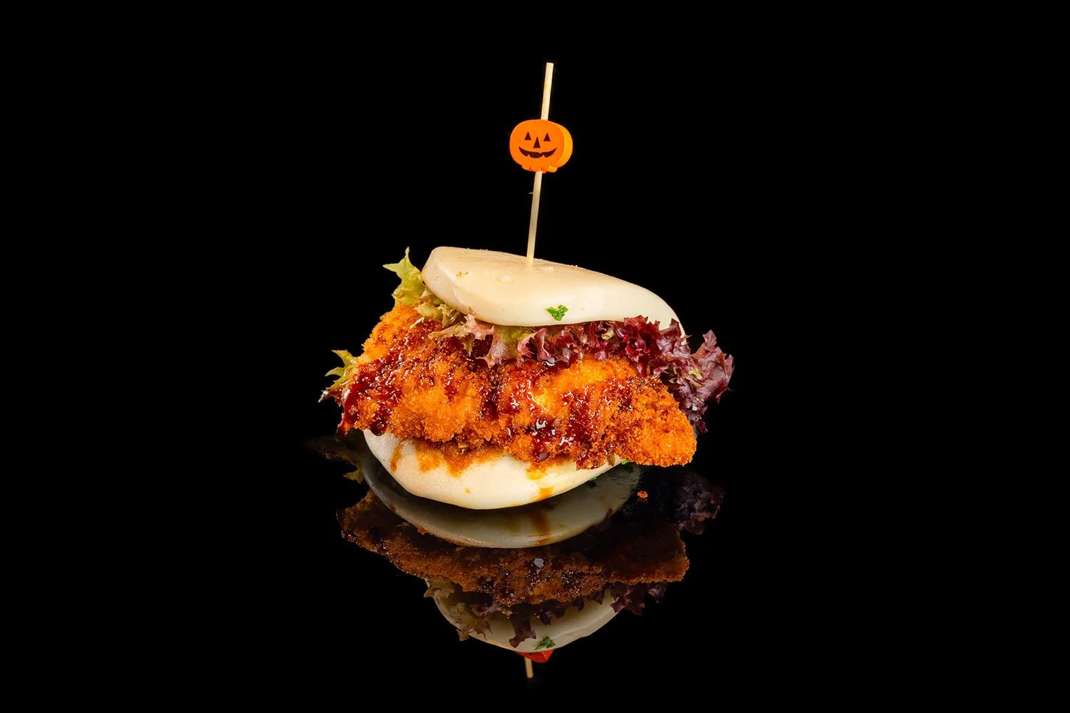 Kleine Sandwich mit frittiertem Hühnchen, Salat, Käse und Halloween-Kürzchen-Schirm auf einer schwarzen Oberfläche