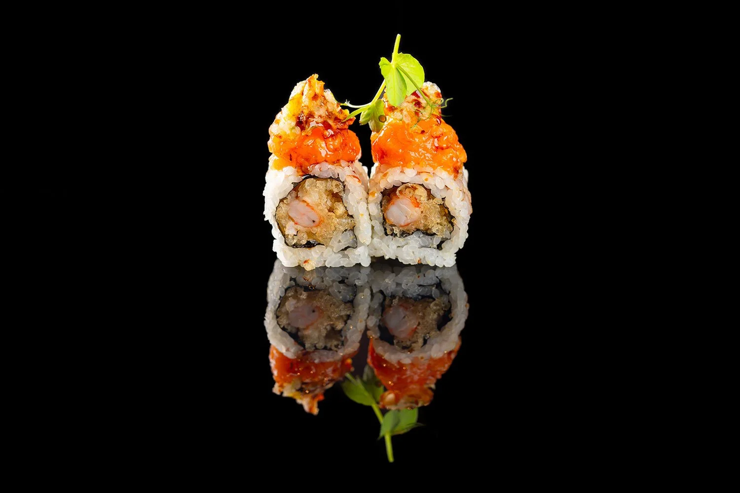 Zwei Sushi-Rollen mit Lachs, Garnelen und Gemüse, mit rohem Lachs und grüner Garnitur auf schwarzem Hintergrund und reflektiert
