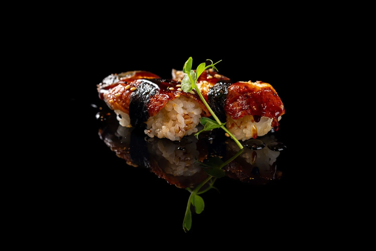 Sushi mit rotem Fisch, schwarzer Algen, Sesam und grüner Kräuter garnitur auf schwarzem Hintergrund