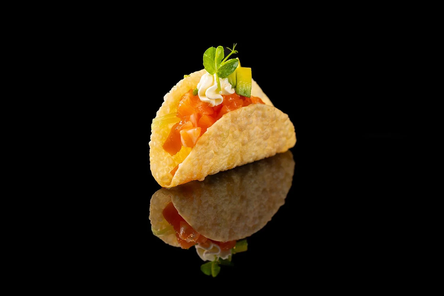 Taco mit Hackfleisch, Tomaten, Käse, Salat und Kresse auf schwarzem Hintergrund