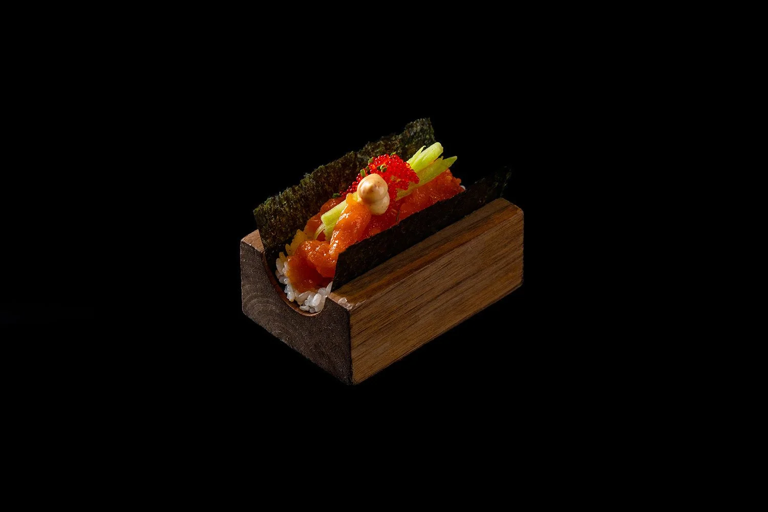 Sushi in einem Holzbehälter mit Nori, rohem Fisch, Gemüse und Garnelen, auf schwarzem Hintergrund