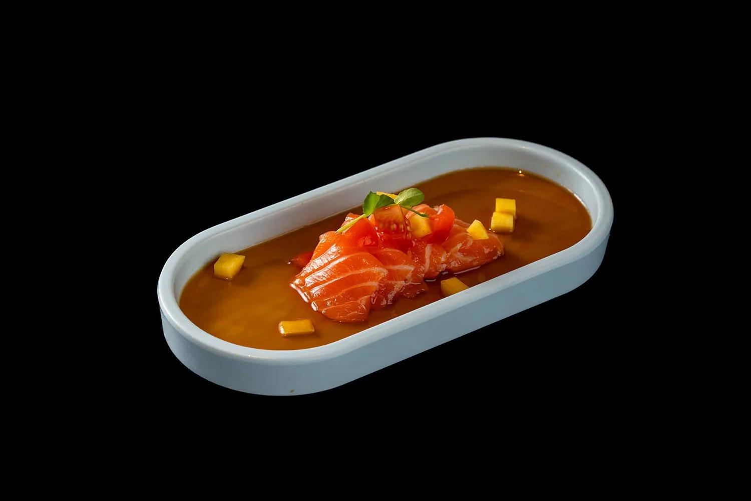 Lachsfilet mit Tomaten und Mango auf einem Teller mit brauner Soße