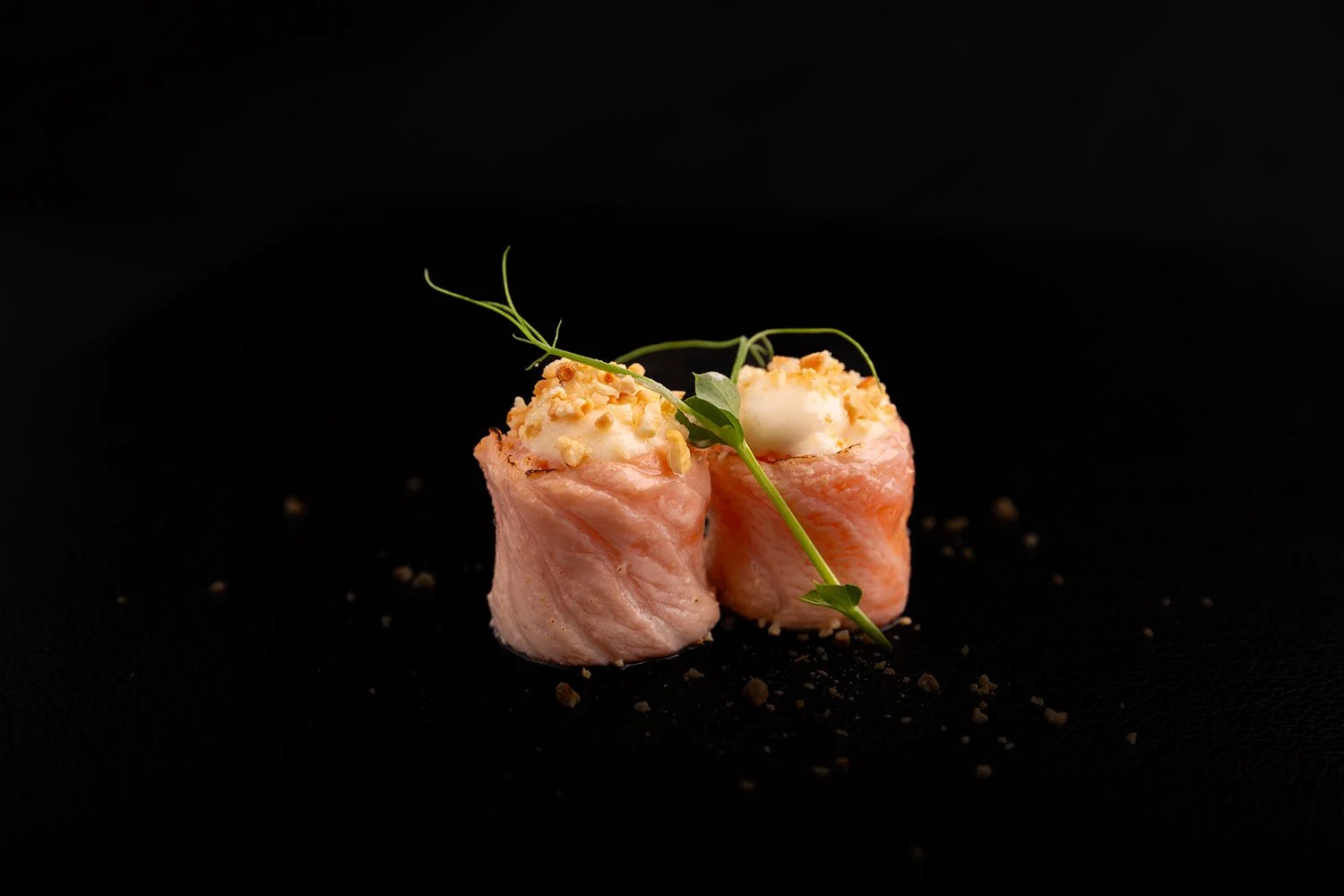 Zwei Bagel mit Putenbrust, Frischkäse, gerösteten Nüssen, frischer Kräuter und Pfeffer auf schwarzem Hintergrund.