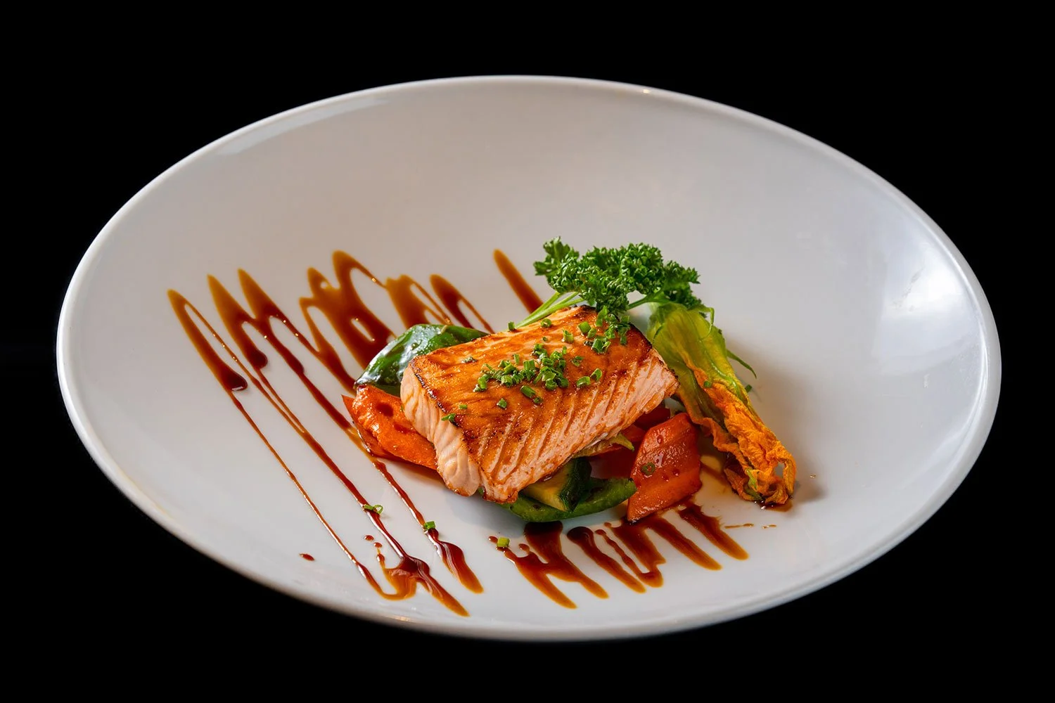 Gegrillter Lachs auf einem Teller mit Gemüse und Balsamico-Reduktion, dekoriert mit Petersilie