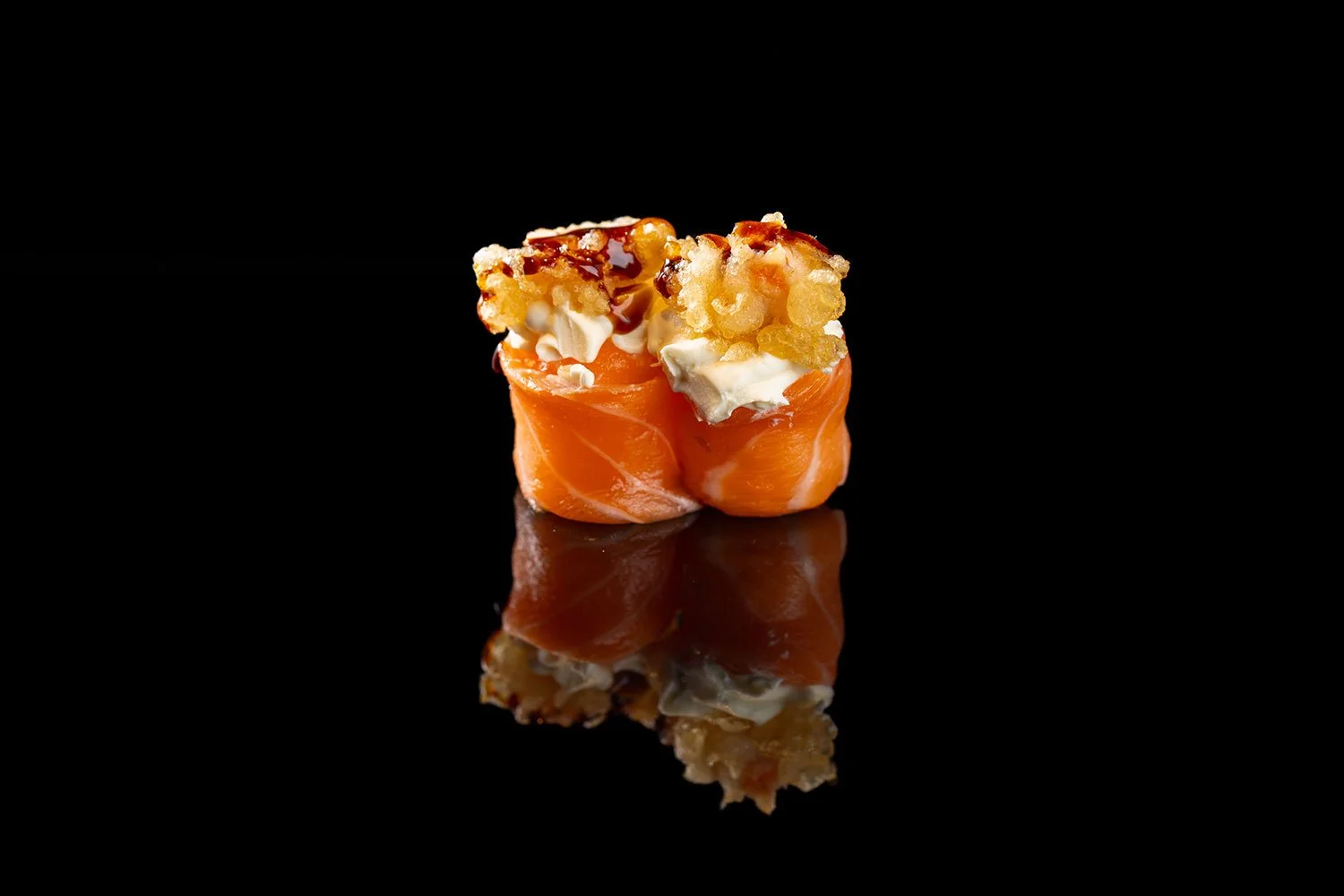 Sushi mit Lachs, Frischkäse und knusprigem Tempura auf schwarzem Hintergrund