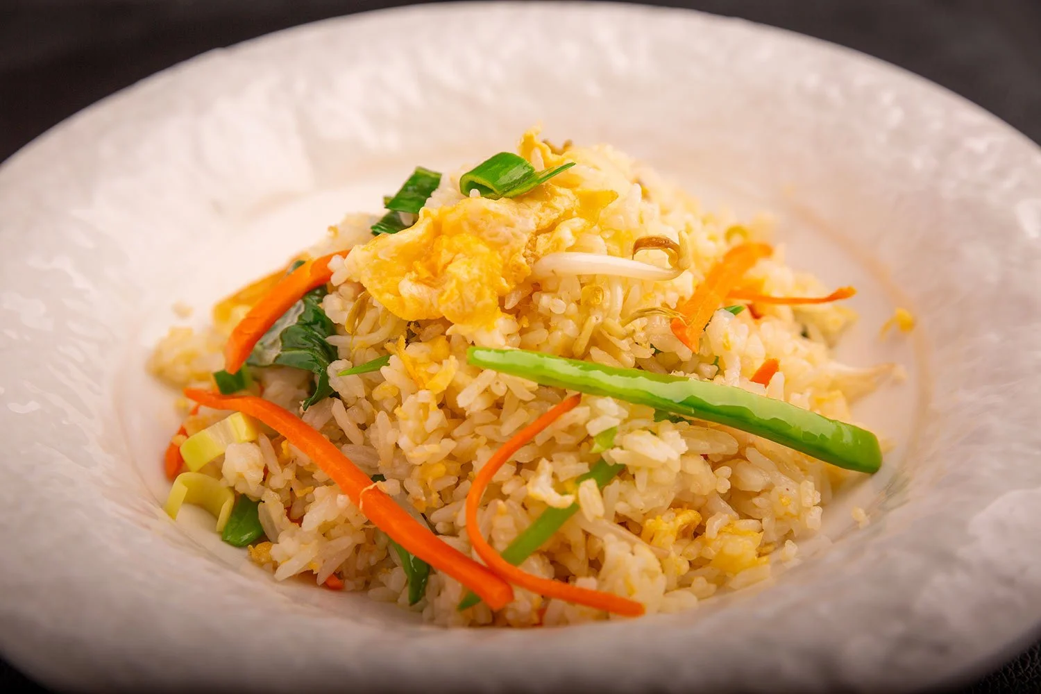 Reis mit Gemüse und Rührei auf einem weißen Teller