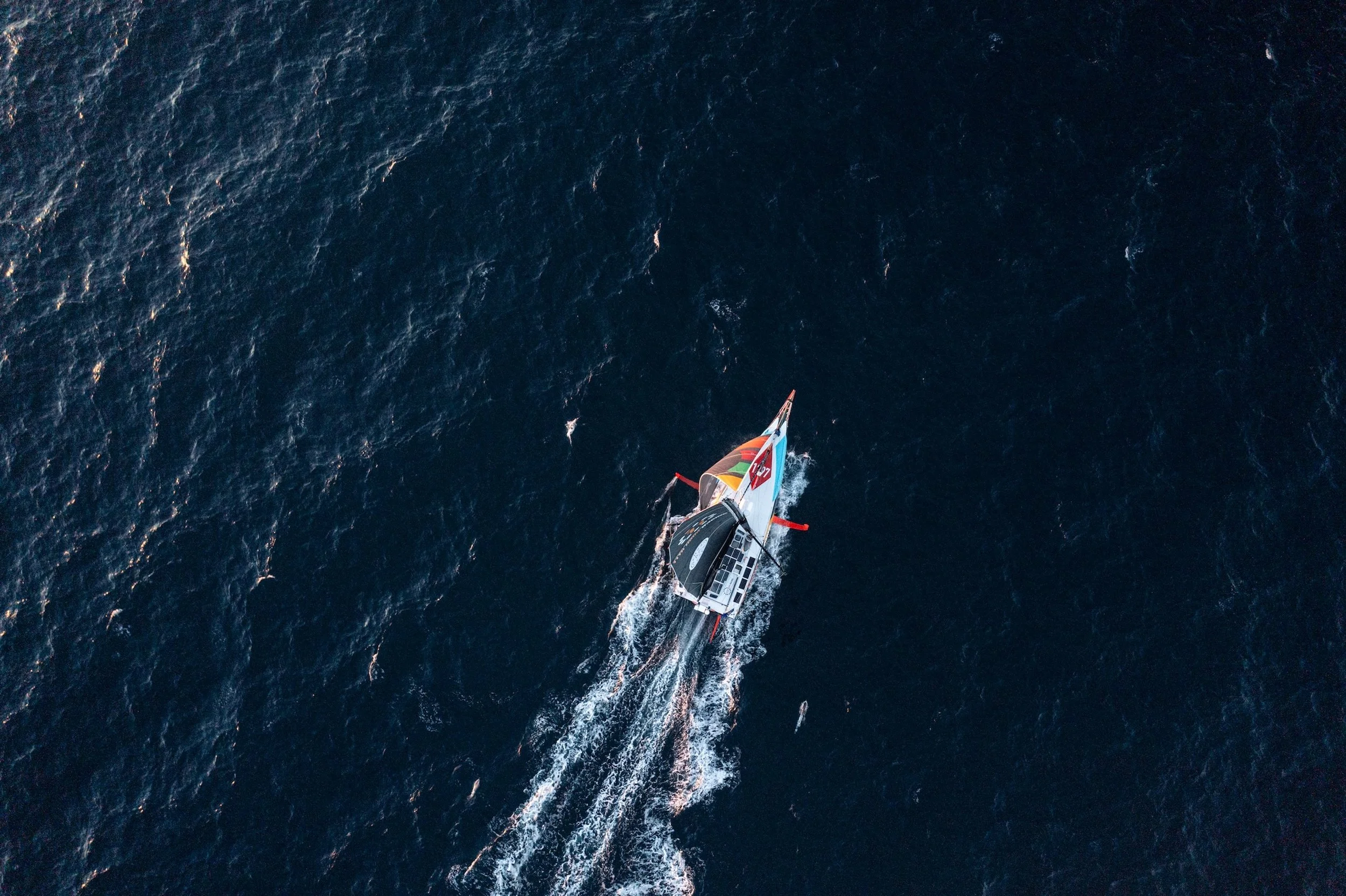 Vista aerea di una barca a vela che naviga sulle acque blu scuro dell'oceano.