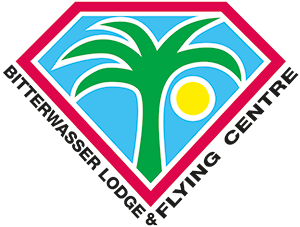 Logo des Bitterwasser Lodge & Flying Centre mit Palme, Sonne und Wasser, eingerahmt von rotem, weißen und schwarzen Linien.