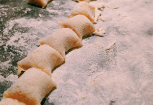 Teigstücke auf einer Arbeitsfläche mit Mehl, Vorbereitung für Ravioli oder Maultaschen.