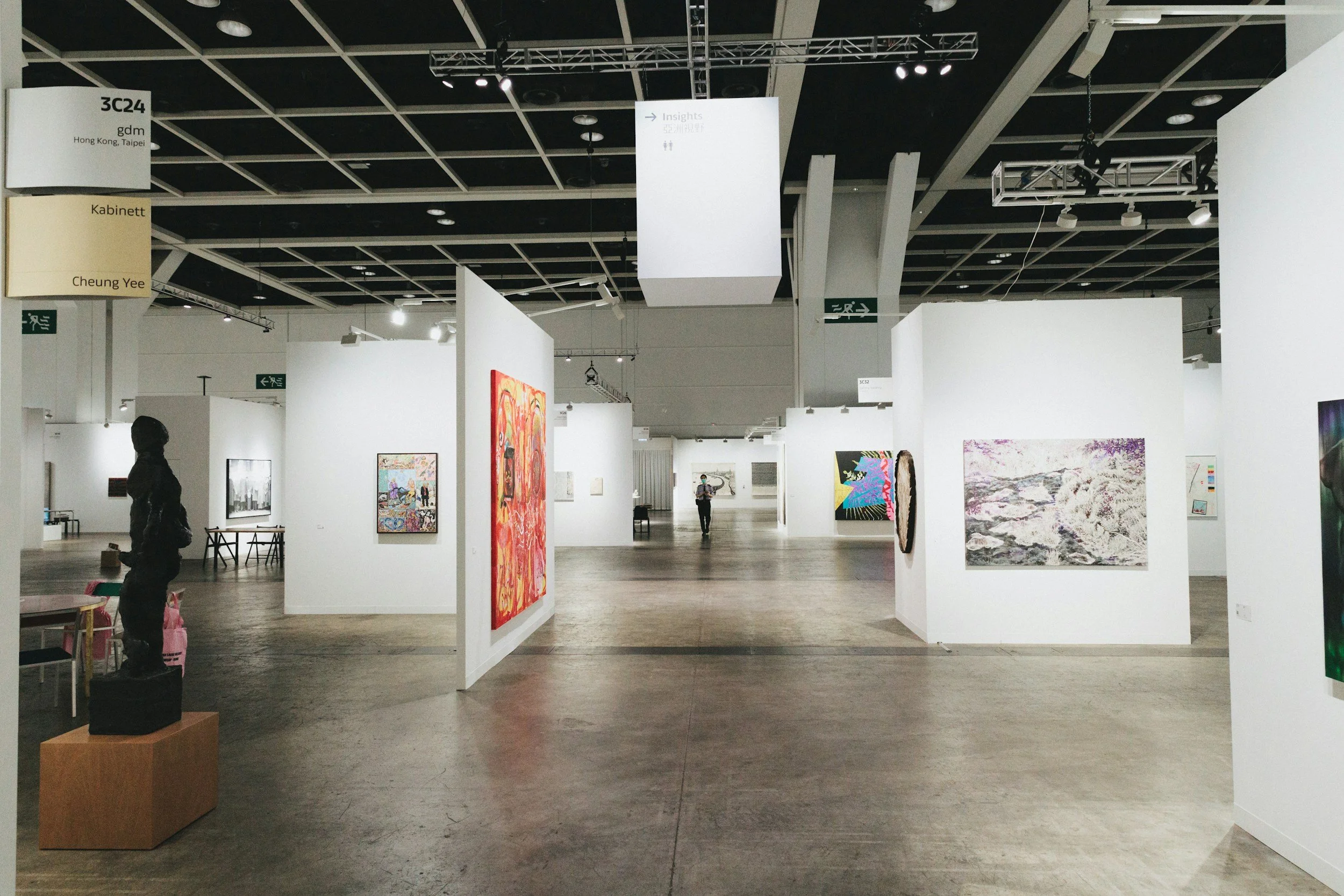 Blick in eine Kunstmesse mit Kojen, in denen Kunstwerke hängen.