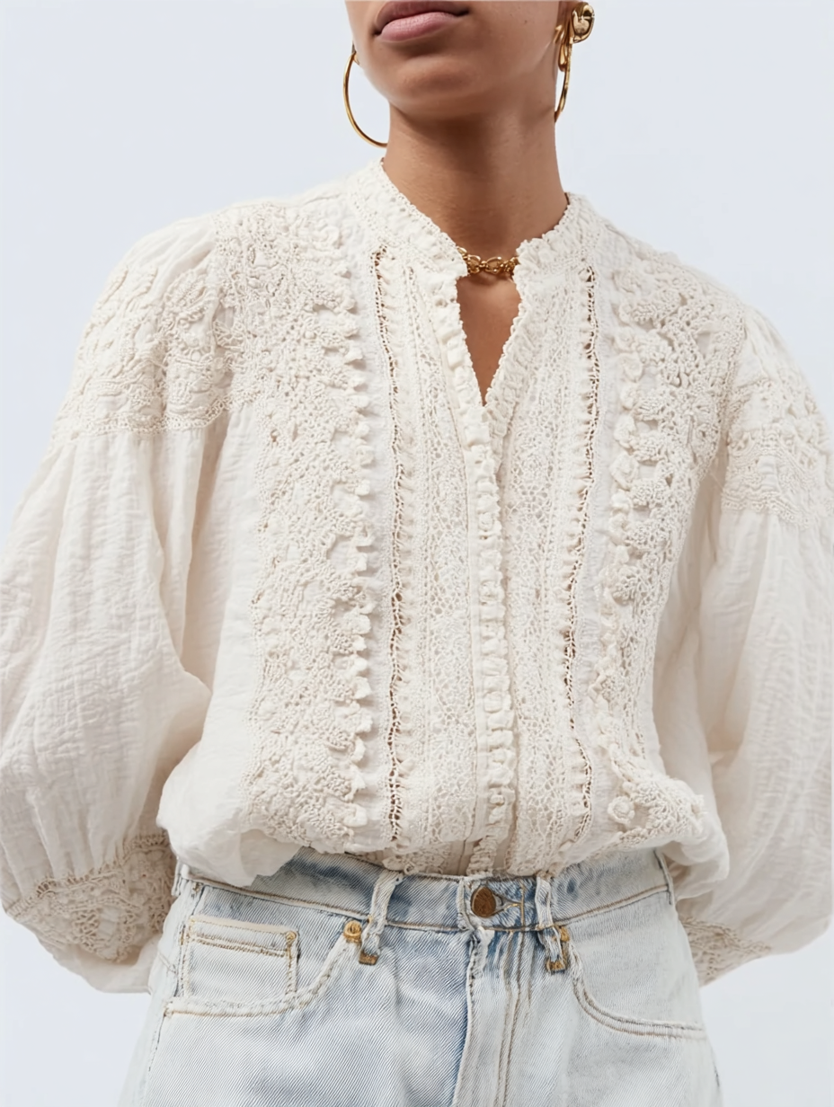 Close-up of a woman wearing a white embroidered blouse with puffed sleeves, gold hoop earrings, and a gold necklace, paired with light-wash jeans.