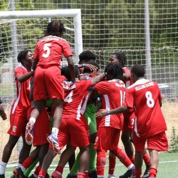 Grupo de jugadores de fútbol infantil en uniforme rojo celebrando un gol en el campo