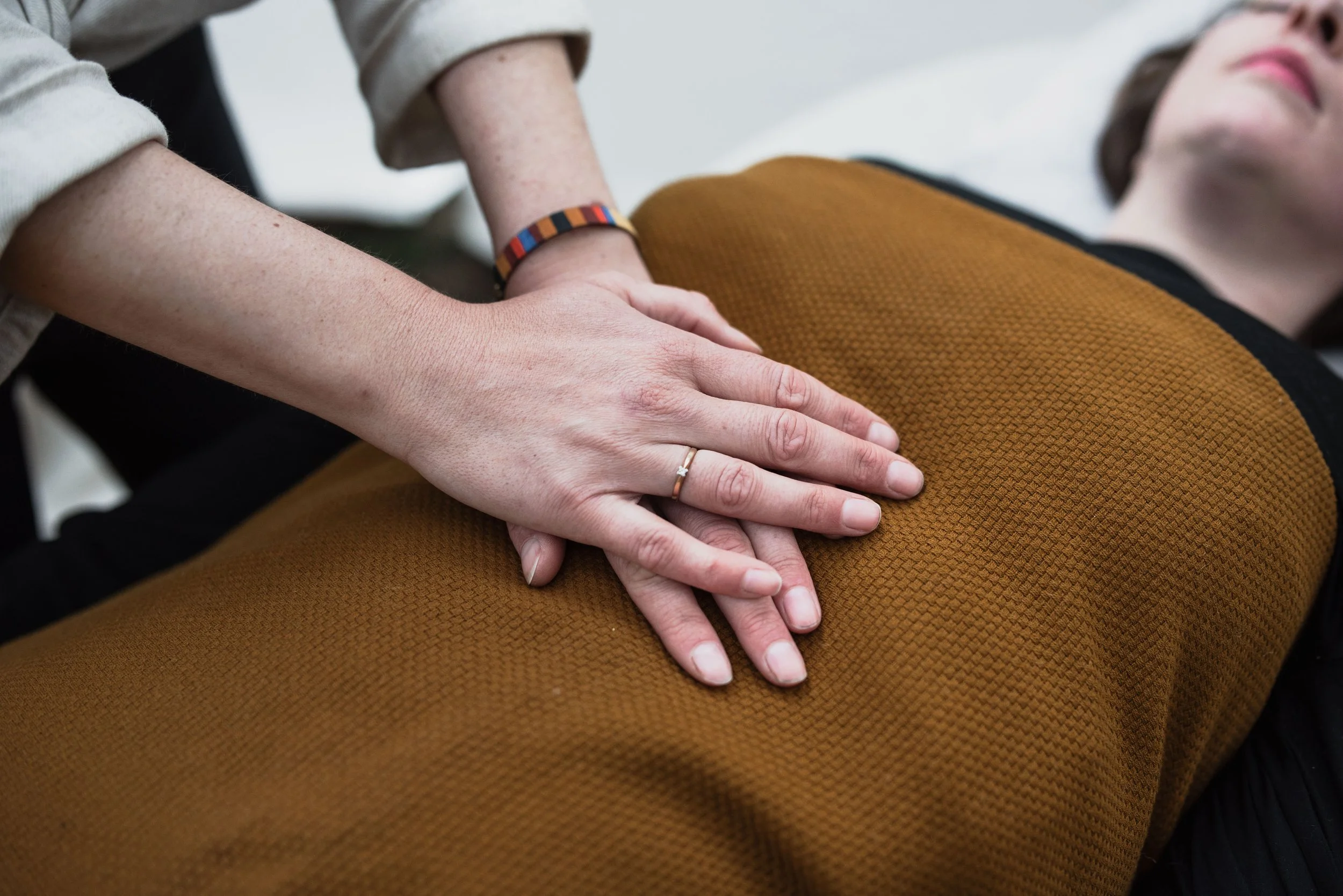 Person performing reiki with her hands on a woman lying on her back.