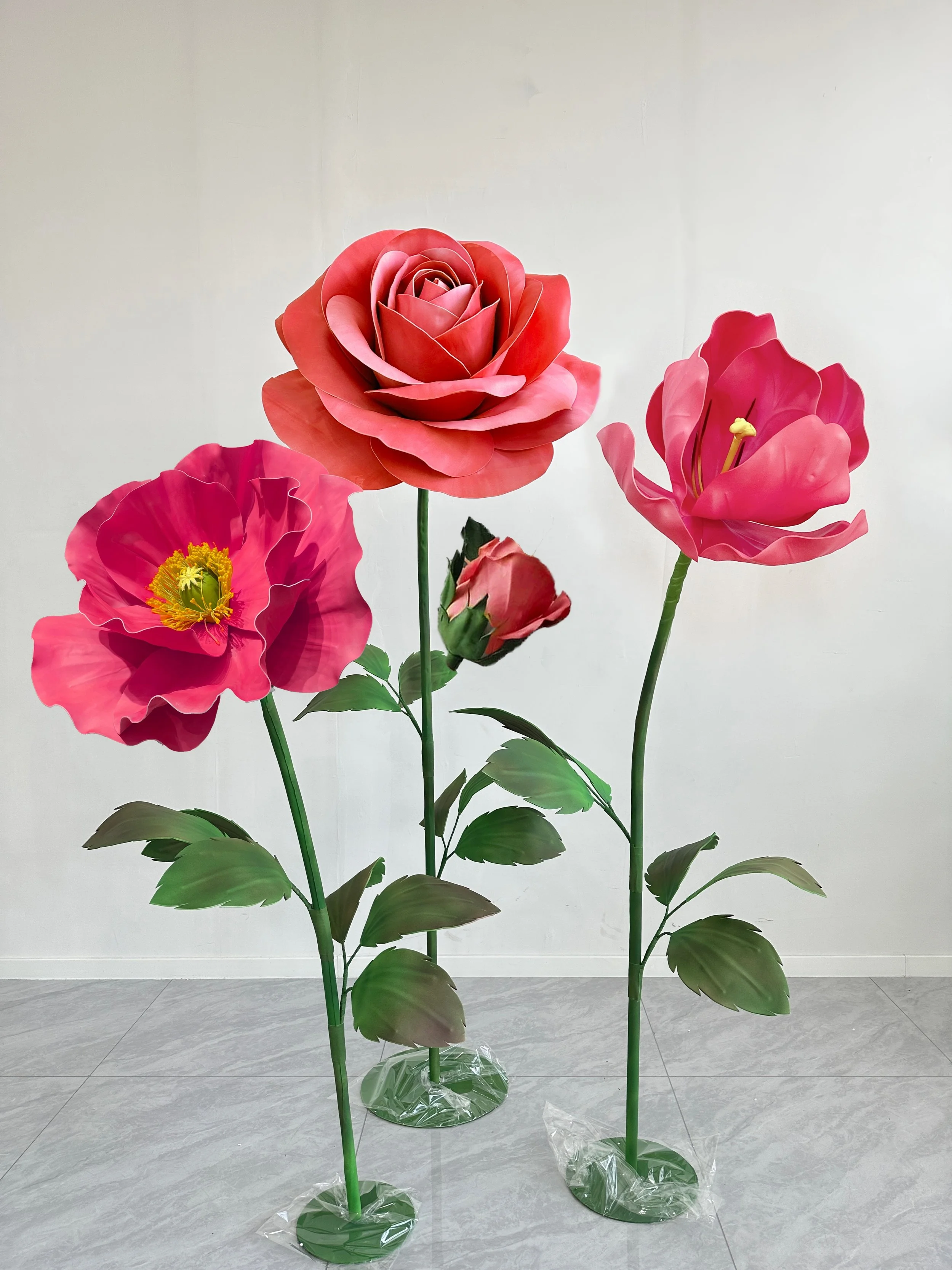 Handmade pink and coral sculptural flowers with green stems and leaves for a photo shoot.