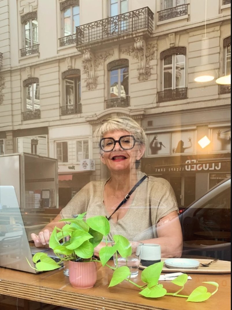 une femme experte en décoration intuitive est assise derrière une vitrine et sourit