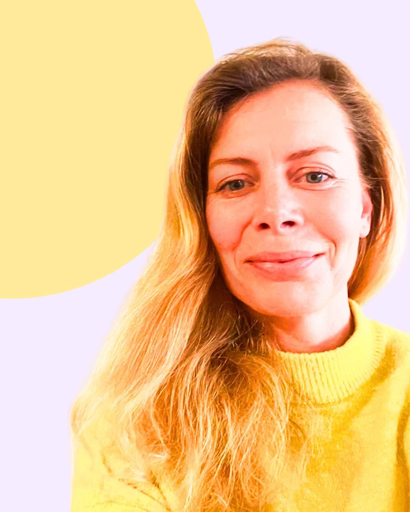 A woman with long, wavy red hair and blue eyes, smiling, wearing a yellow sweater, with a light-colored background featuring a yellow circle.