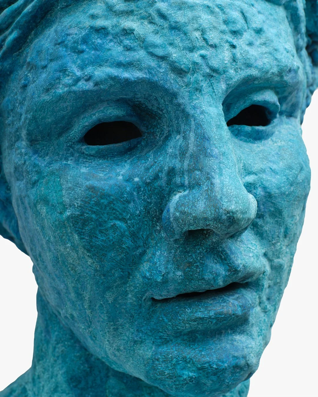 Close-up of a blue textured sculpture of a child's face with hollow eyes and closed lips.