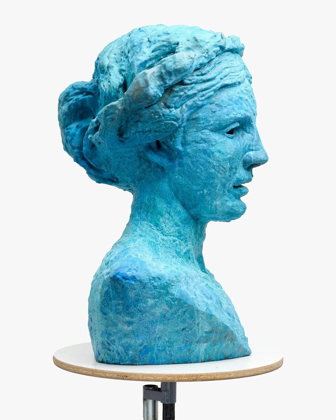 A bust of a woman painted in blue, with detailed hair and facial features, displayed on a round wooden base.