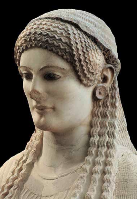 Close-up of an ancient marble sculpture depicting a woman with detailed, wavy hair and a circular earring against a black background.