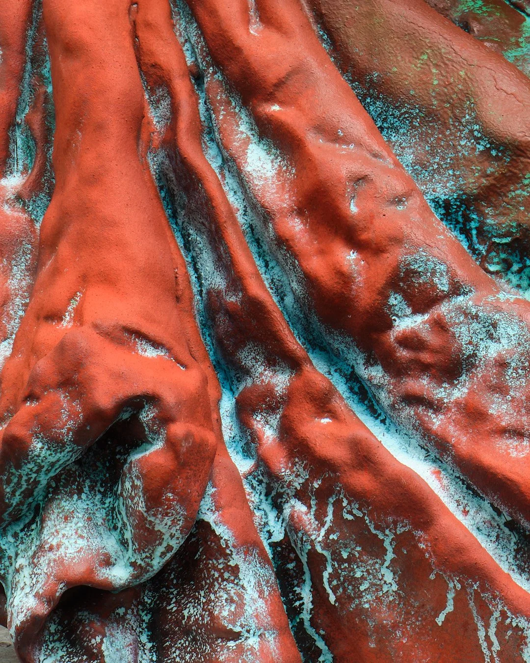 Close-up of a textured fabric with reddish-brown, teal, and white colors, showing folds and creases.