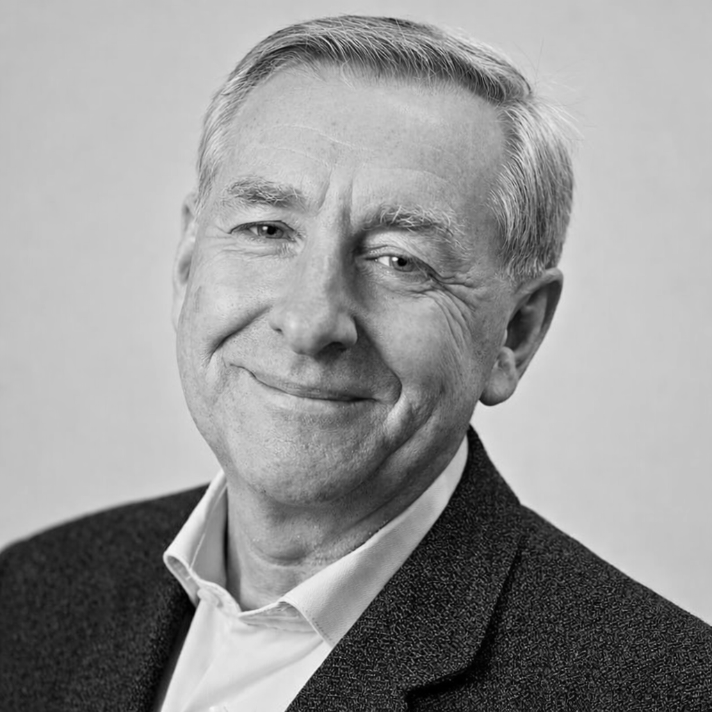 Black and white photo of a smiling middle-aged man with short, gray hair, wearing a suit jacket and collared shirt.