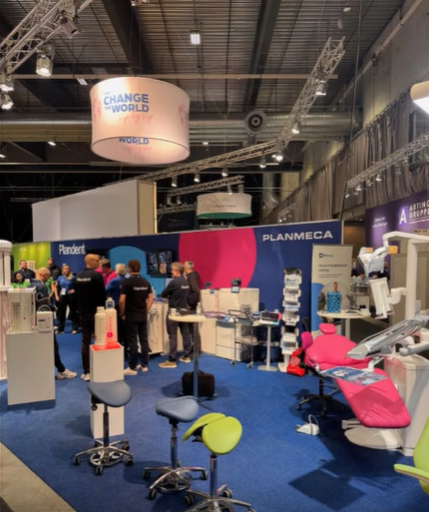 Trade show booth with attendees, displays, and a large circular overhead sign that says "Change the World."