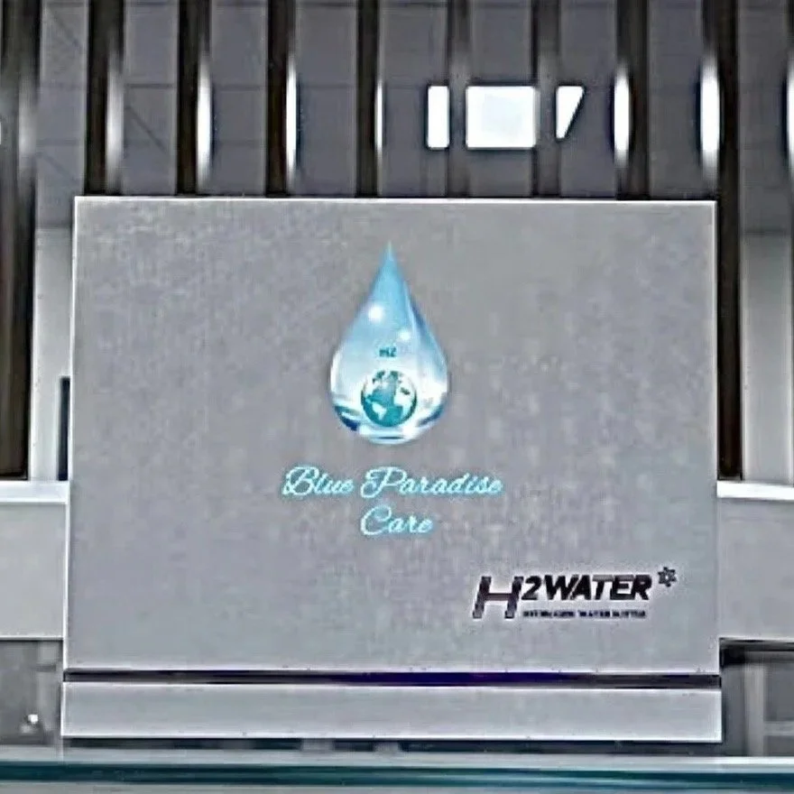 Panneau publicitaire pour Blue Paradise Care, une marque de produits à base d'eau, avec un logo représentant une goutte d'eau et la Terre, situé sur un mur en métal.
