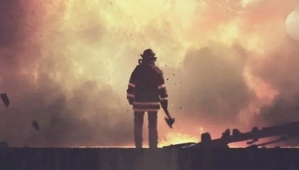 A firefighter in uniform standing on a rooftop at night with a background of smoke and flames.