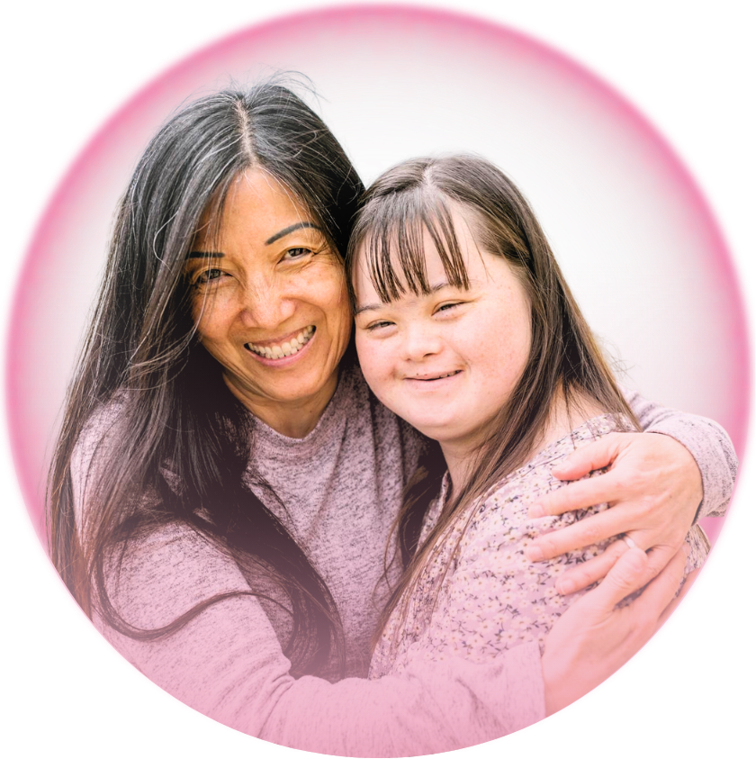 A woman with long dark hair and a girl with straight brown hair, both smiling and hugging each other.