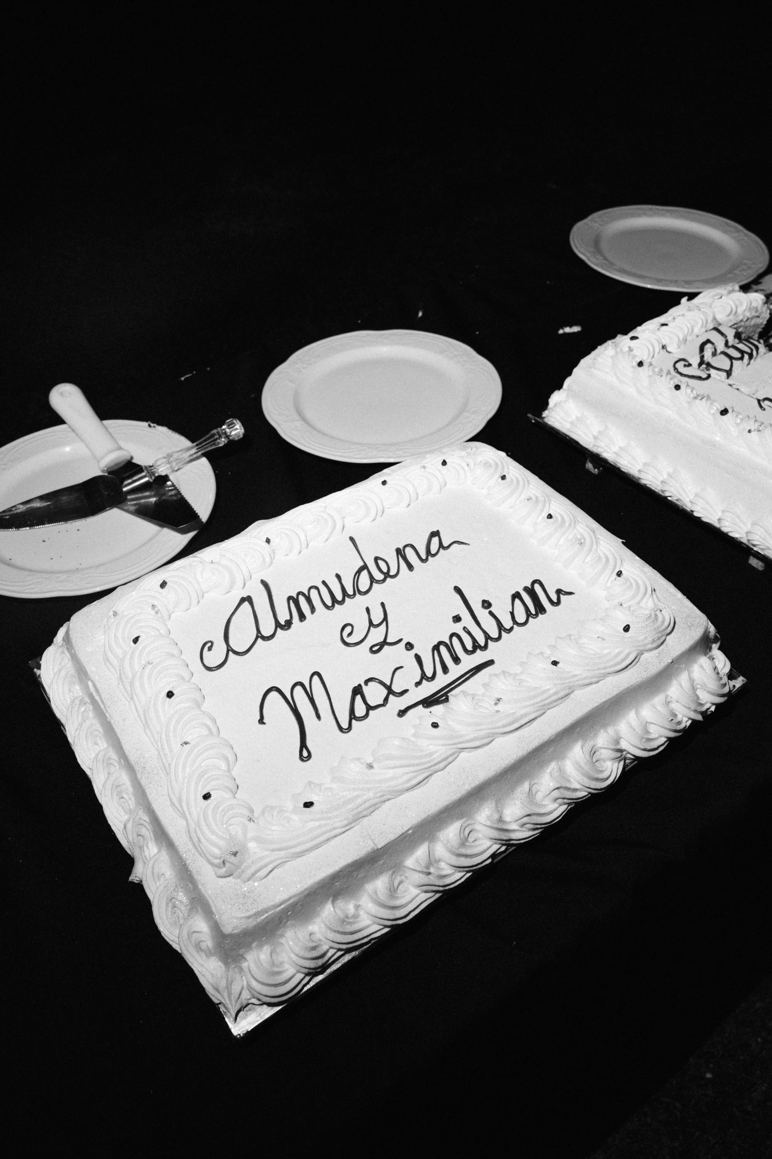 A rectangular wedding cake with white frosting and decorative piping, inscribed with 