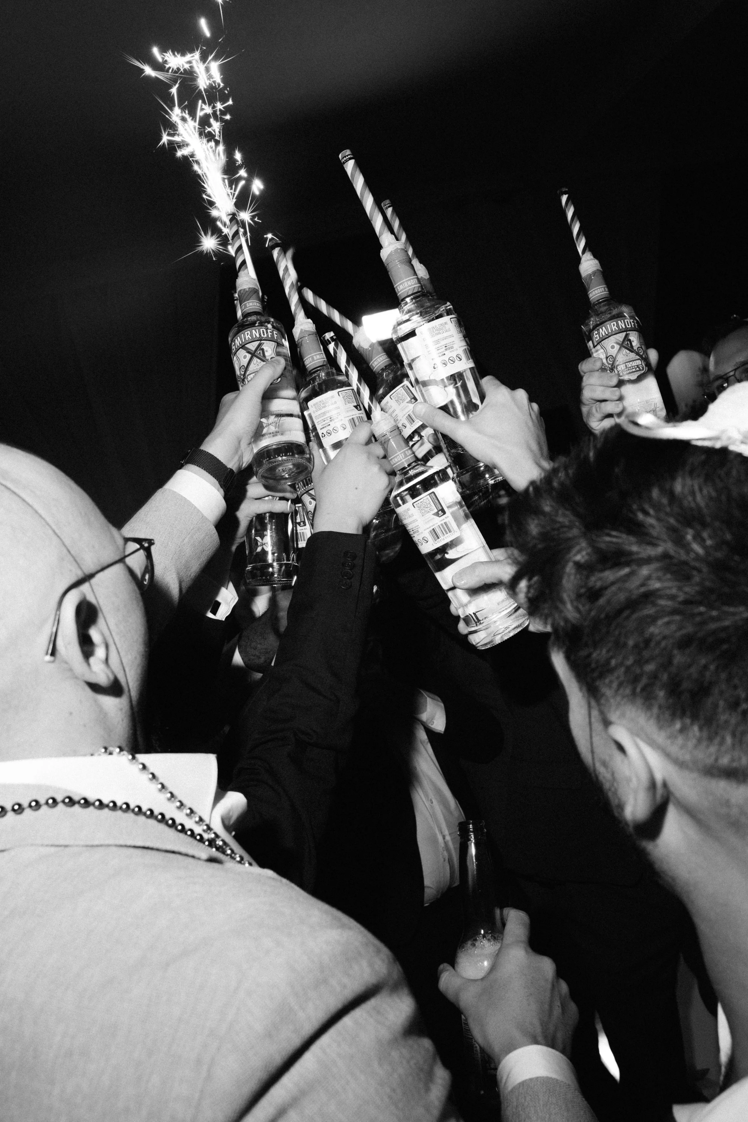 People raising Smirnoff vodka bottles with sparklers attached, celebrating at a party.