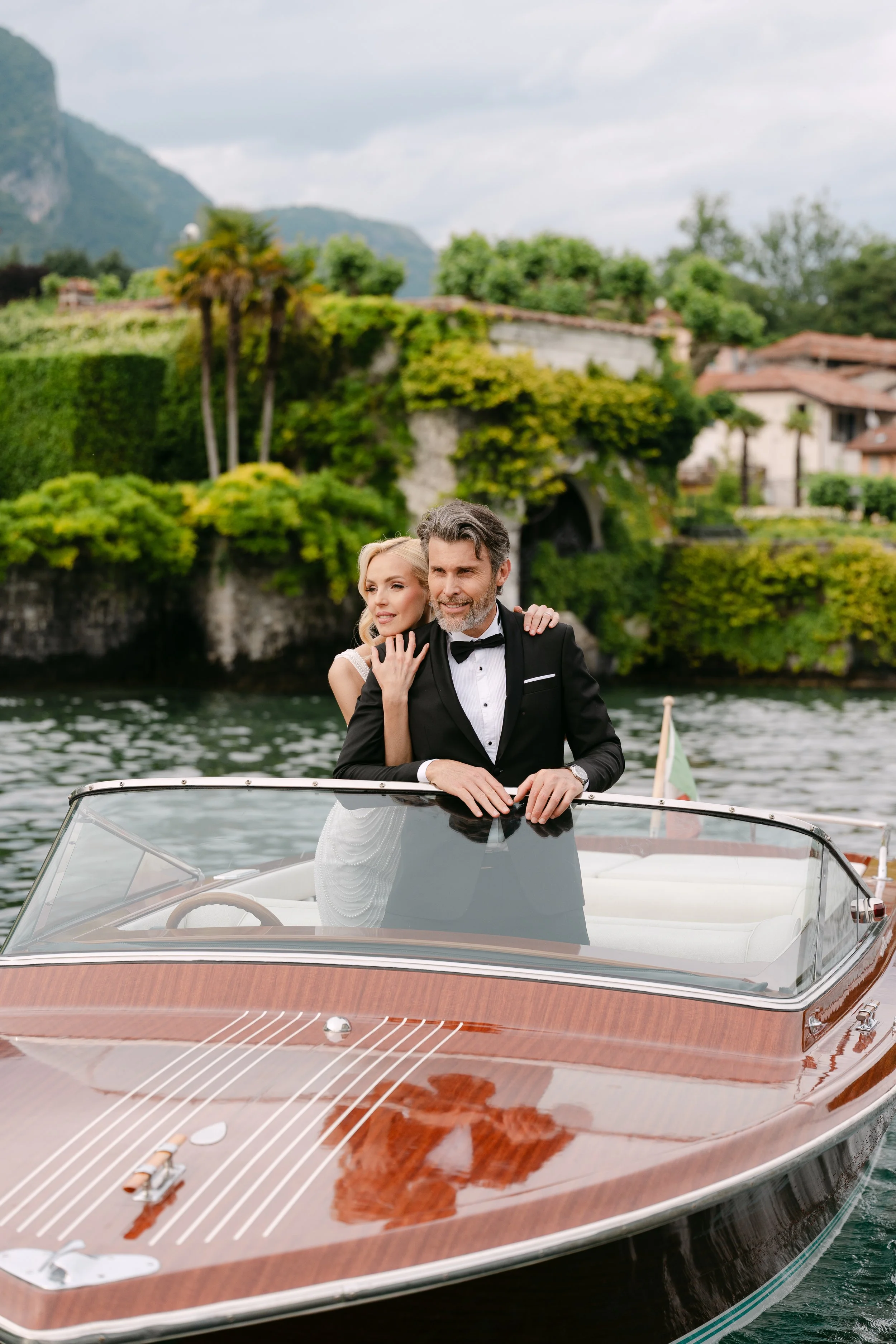 Editorial wedding photography: Elegant couple on a vintage wooden boat (Riva) at Lake Como, Italy.